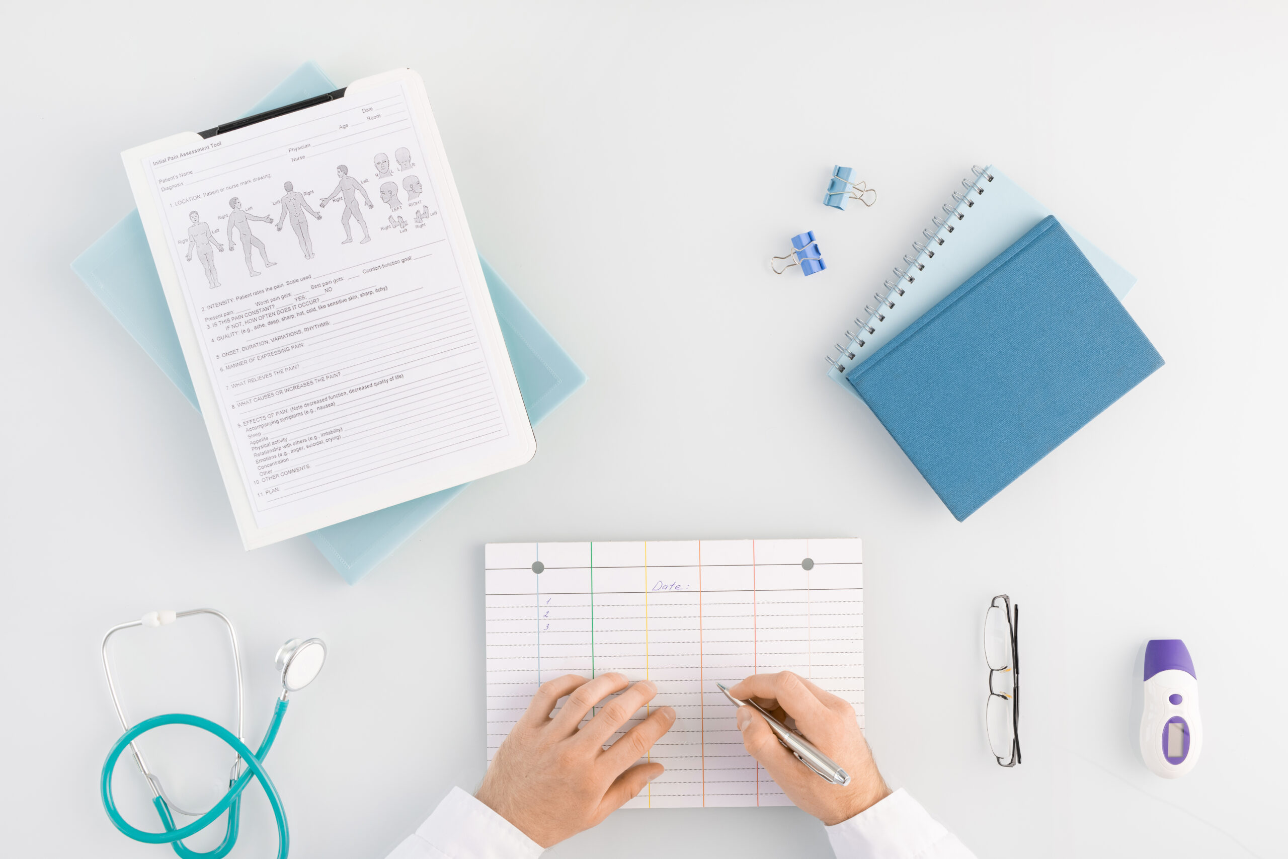 Flat layout of hands of contemporary clinician with pen over medical card Flat layout of hands of contemporary clinician with pen over medical card going to write down information about patient by workplace