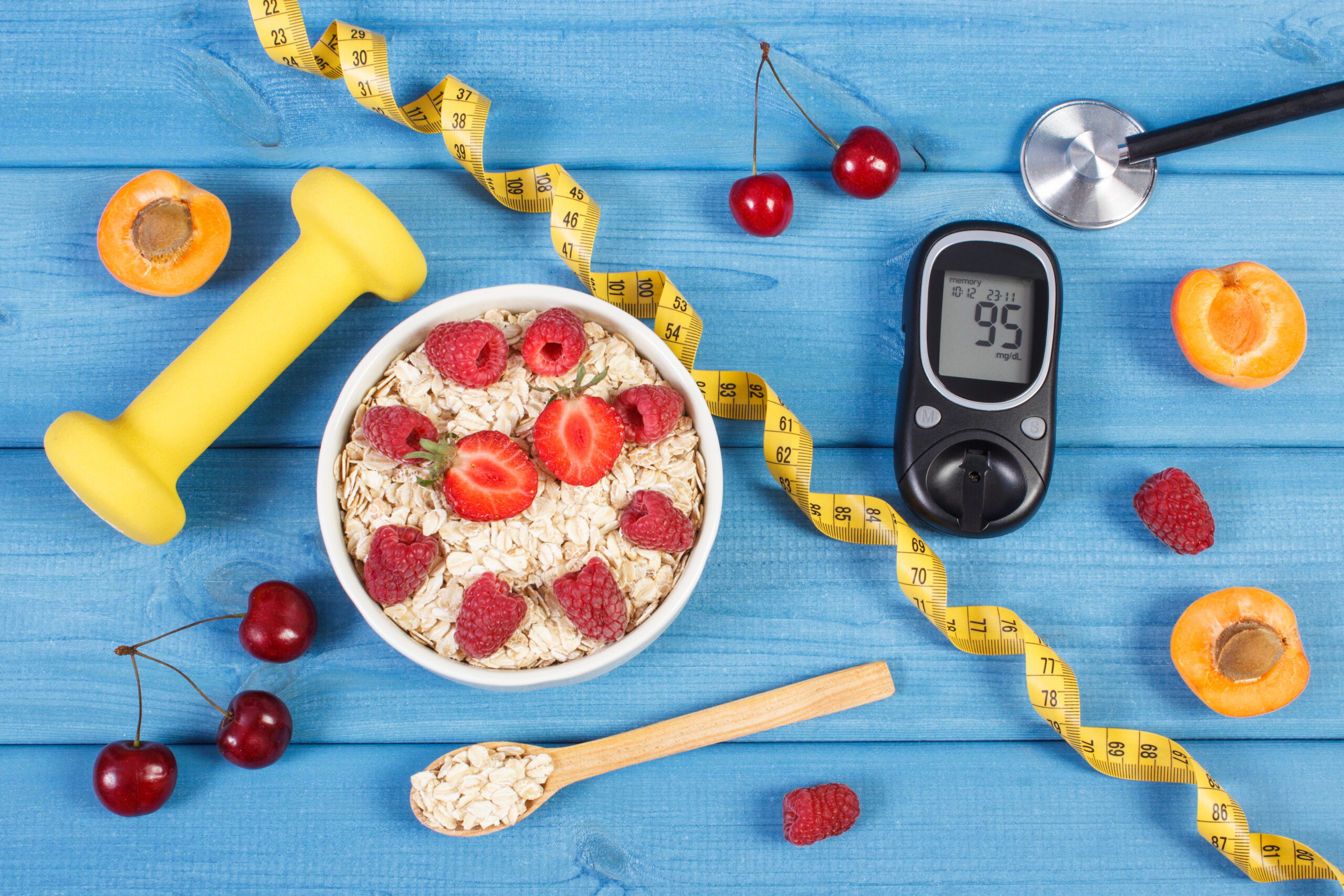 Glucometer, oat flakes with fruits, dumbbells and centimeter, concept of diabetes, slimming and healthy lifestyle Glucose meter with result of sugar level, oat flakes with fruits, tape measure and dumbbells for fitness, concept of diabetes, diet, slimming and healthy lifestyles