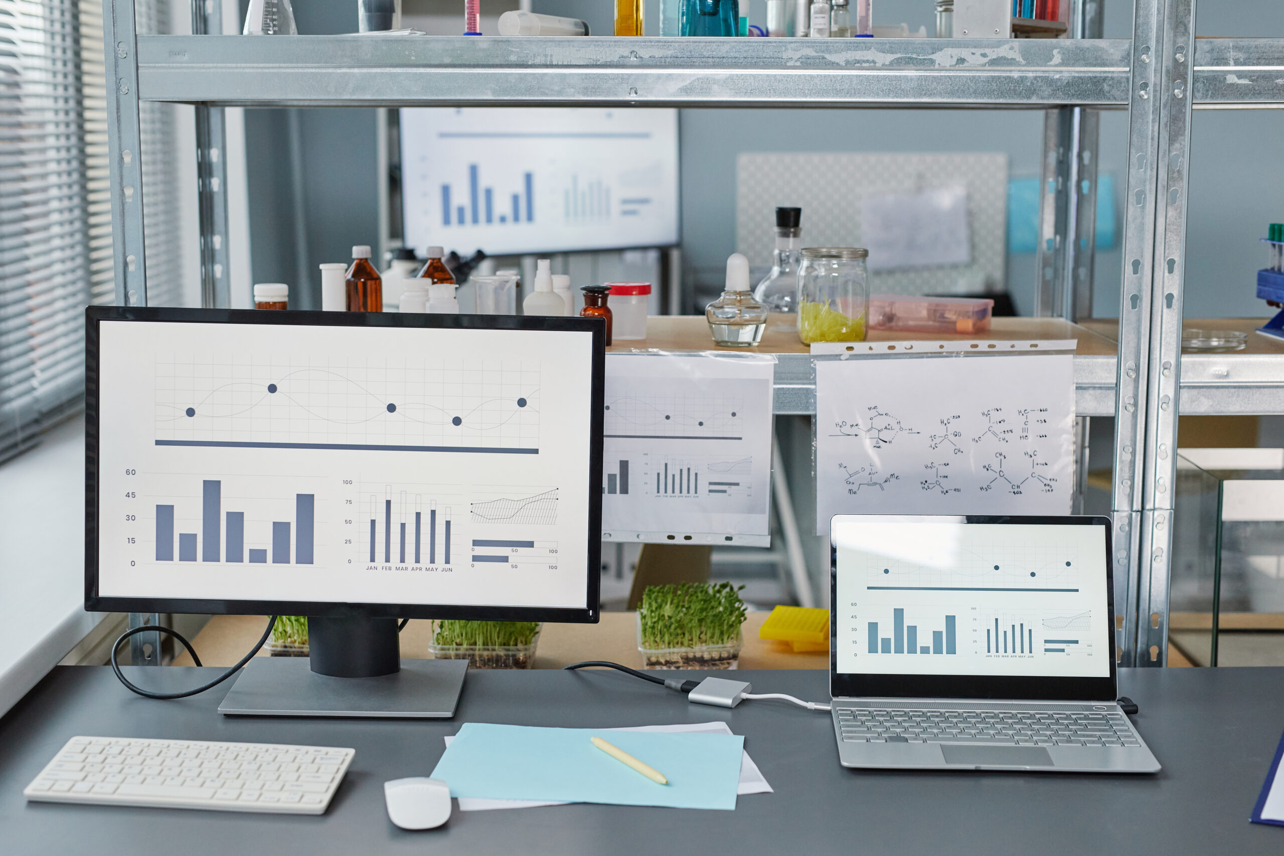 Research of scientist in the laboratory Image of computers with graphics on the screen and test tubes with samples on the shelves for scientific experiment in the lab