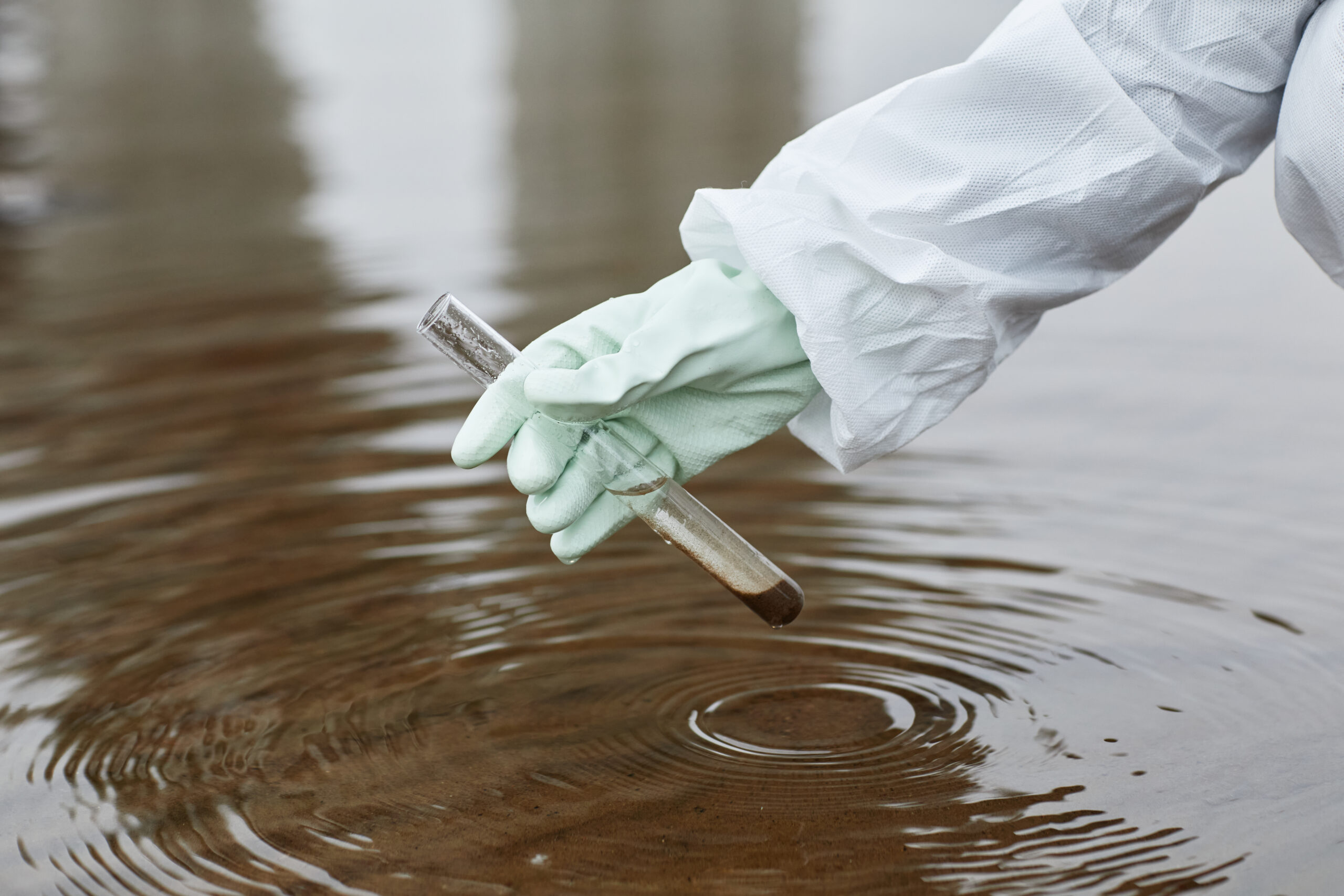 Scientist Taking Water Probe Close Up Close up of unrecognizable scientist wearing hazmat suit collecting water samples, focus on gloved hand holding test tube, copy space