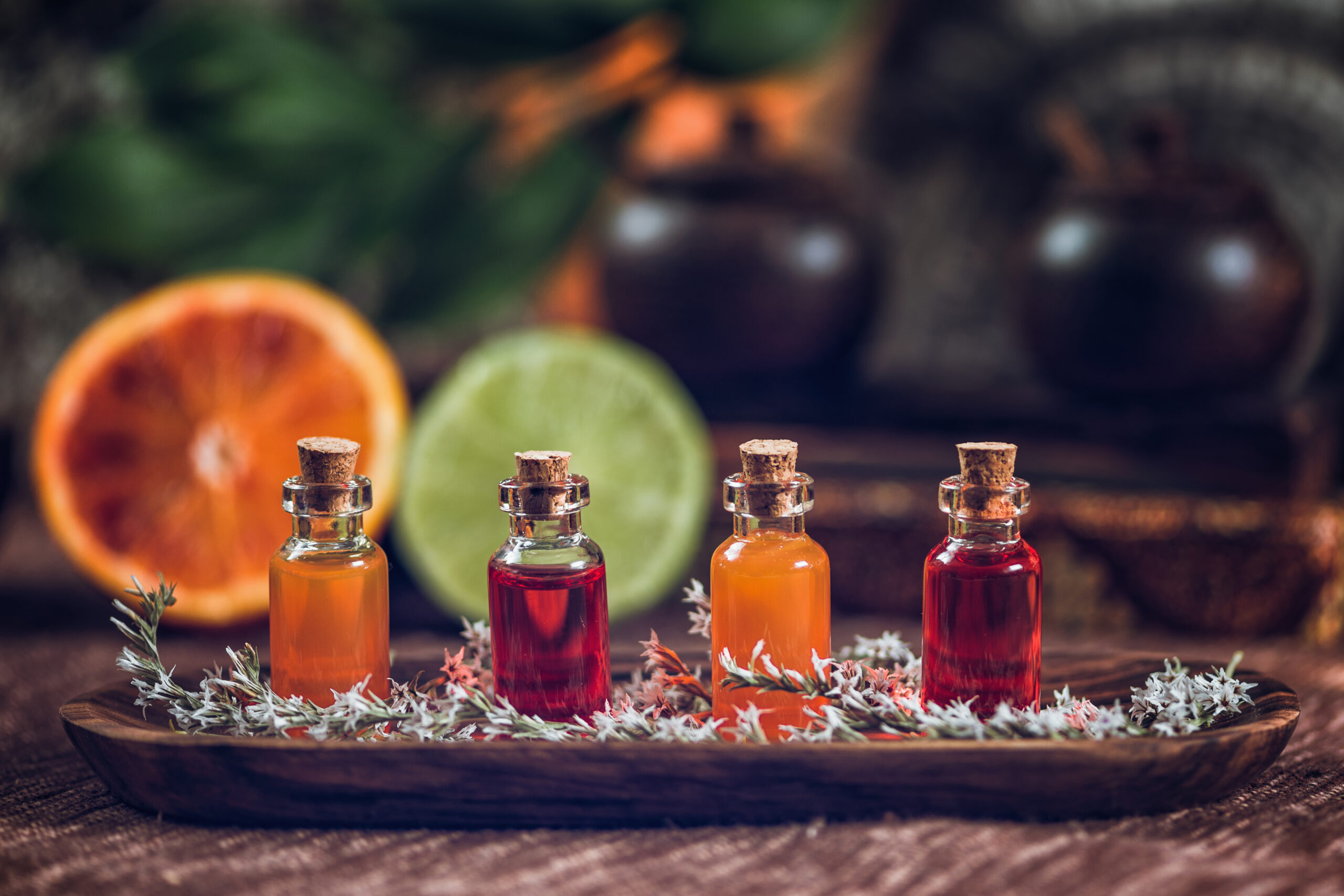 Aromatherapy Bottles filled with red and orange essential oils on wooden board. Fresh citrus fruit, orange and lime cut in half. Aromatherapy relax concept